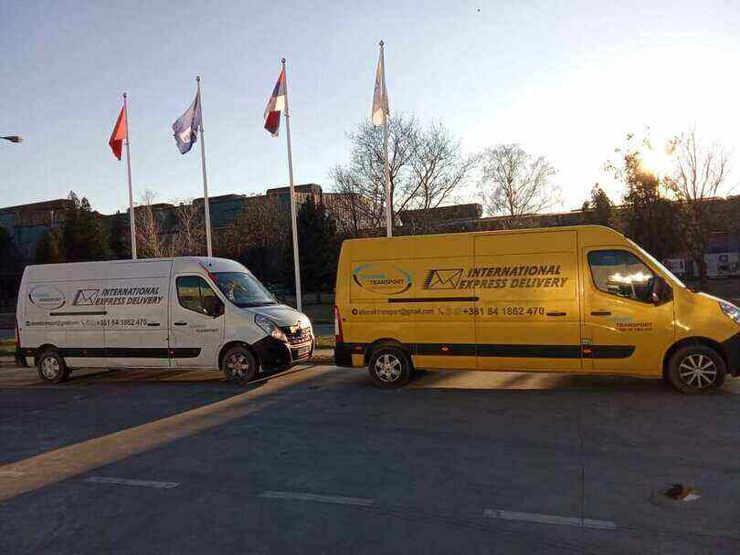 Žuti i beli kombi parkirani ispod zastava